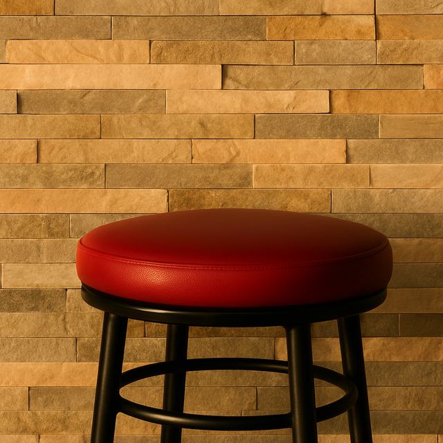Un tabouret rouge devant le parement de pierre du comptoir